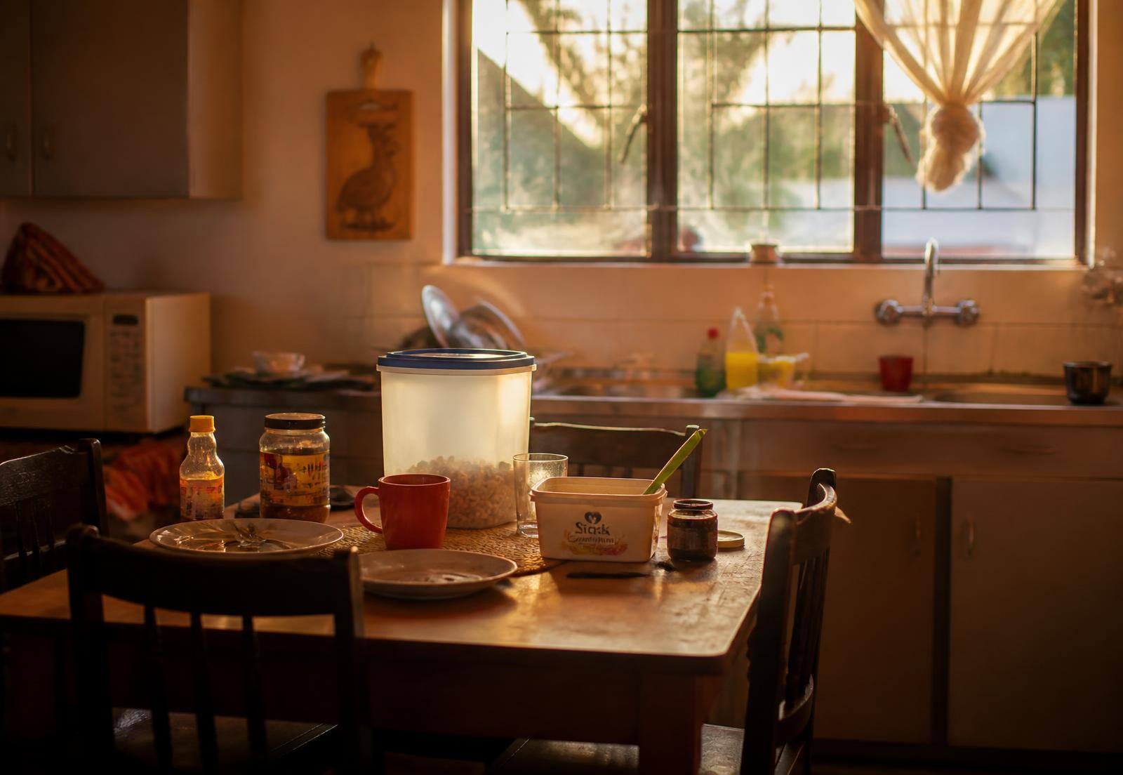 A kitchen table at golden hour with the day's clutter still on it